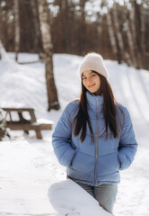 Fototapeta na wymiar Beautiful woman in fashionable winter clothes (blue jacket and jeans) outdoors. Stylish female model walking in winter nature