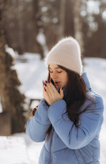 Young girl breathes on her hands to keep warm at cold winter day. Girl warms her hands with a warm breath