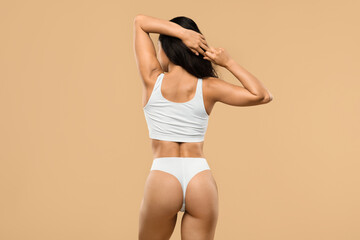 Obraz premium Body Care. Rear View Of Slim Female In Underwear Over Beige Background