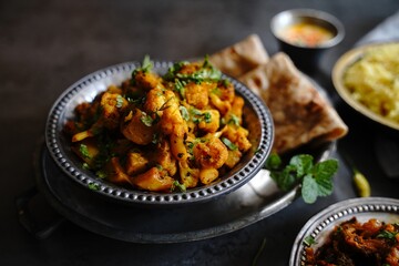 Homemade aloo Gobi - Indian vegetarian curry made with potatoes and cauliflower served with rice and roti