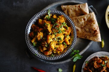 Homemade aloo Gobi - Indian vegetarian curry made with potatoes and cauliflower served with rice and roti - obrazy, fototapety, plakaty