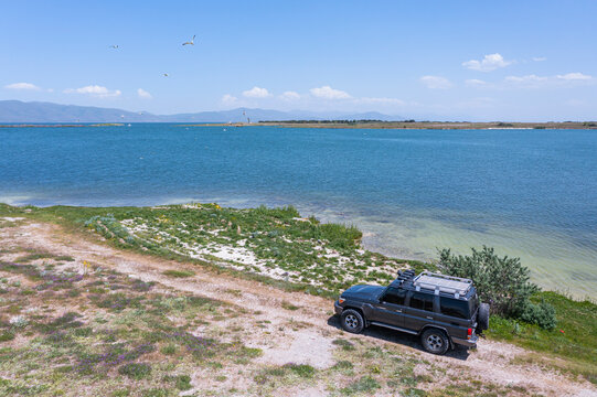 Norashen, Armenia - 30 May 2021: Aerial view of an off road car driving a scenic road along the Lake Seven coastline, Armenia.