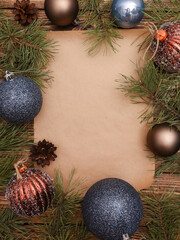 Festive traditional glittering blue, brown Christmas balls, ornament, pine branches, around blank craft sheet of paper. Xmas template for text, New Year, winter holiday concept. Copy space