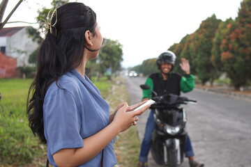 Online motorcycle taxi driver waving hand to customer. Customer waiting driver to pick up on city...
