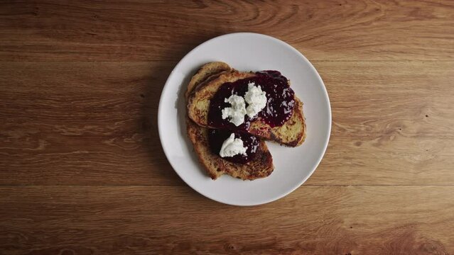 Home chef serving French toast with homemade jam and soft goat cheese. Closeup shot. High angle.