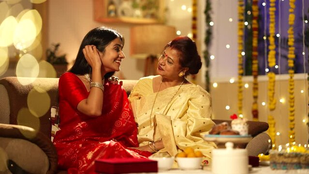 Pretty Indian women on Diwali-A beautiful woman talking to her young daughter.yhey both are wearing saree.well decorated home,hindu festival concept.