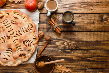 Apple pie and black coffee. Bakery food, fresh red apples, cinnamon spice, espresso cups, honey in bowl on dark rustic wooden table background. Traditional autumn dessert flat lay