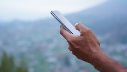 Person using mobile phone. Closeup of business man holding a phone in hand, checking news or...