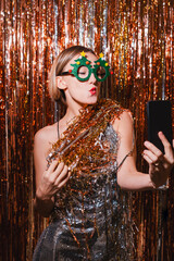 Happy woman taking selfie on smartphone celebrating New Year.