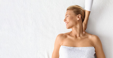 Wellness Concept. Beautiful middle aged woman getting relaxing neck massage at spa