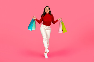 Young Happy Woman Walking With Shopping Bags In Hands On Pink Background