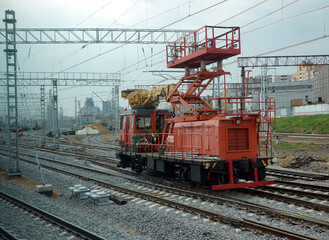 Fototapeta na wymiar Repair of a contact network at a railway junction, a locomotive with a raised repair platform stay on the rails