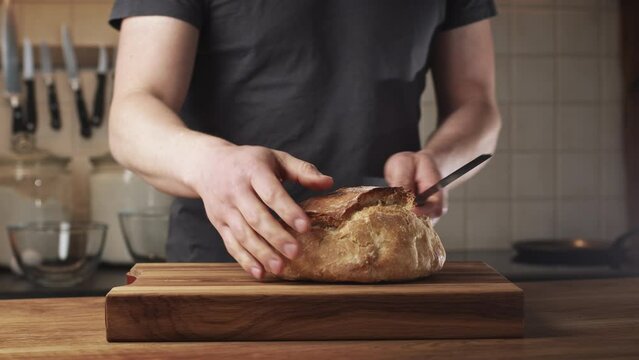 Cutting freshly baked homemade bread on a wooden cutting board. Low angle shot. Home cooking concept.
