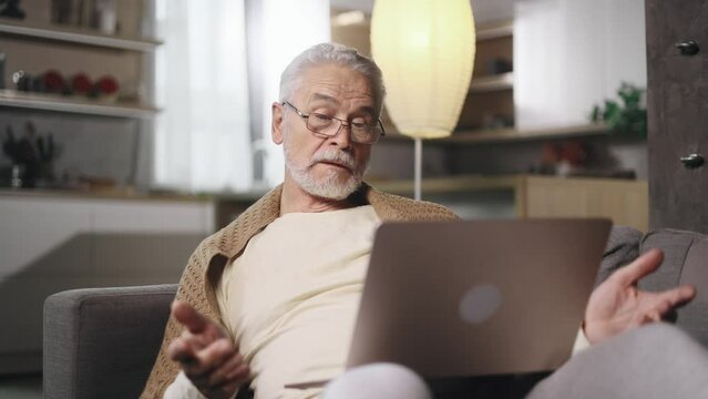 Nervous grey haired male closed laptop computer with unsuccessful business project at light home Stressed senior man expressing negative emotion while has professional problem mistake error indoors