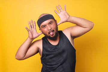 Funny goofy crazy bearded fat man in sportswear with cheerful silly face expression on yellow background