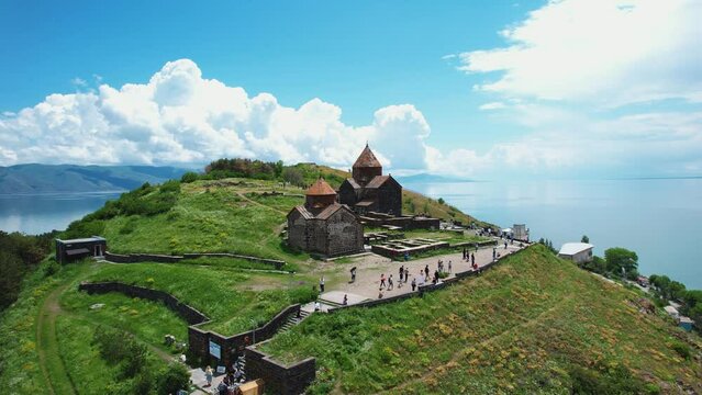  Aerial view monastery on mountain. Drone fly to ancient church Sevanavank in Armenia, Caucasus. Tourists walking near church. Travel and tourist destinations of Armenia. Famous touristic place. 