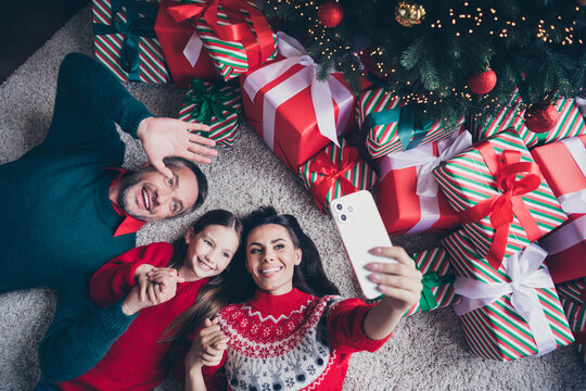 Above view portrait of beautiful family laying floor hold hands waving make selfie x-mas tree house indoors