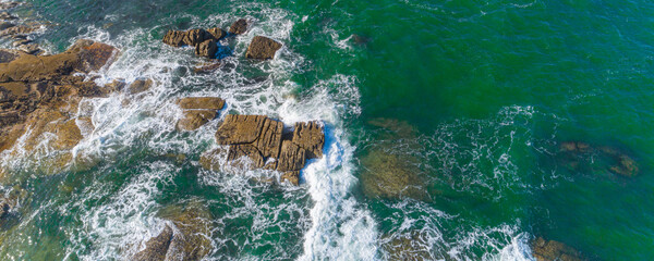 aerial drone view of a rocky coastline and the foam of the waves