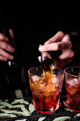 Bartender pours alcohol into a glass with ice using a jigger. Mixing an alcoholic cocktail in a nightclub, pub, restaurant