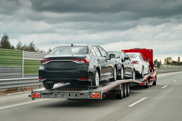 Tow truck with a cars on the highway road. Tow truck transporting car on the autobahn. Car service...