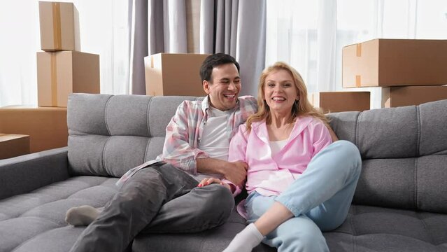 Happy family sit on sofa home portrait. Love couple move into house. Smile people look camera. Fun girl jump couch. Joy adult buy real estate concept. Funny guy rent flat. Romantic hug. Man have rest.
