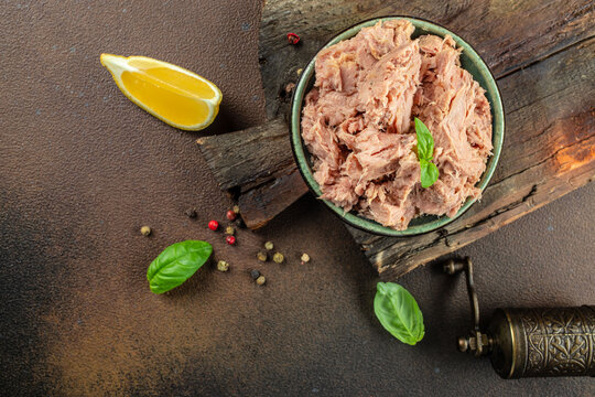 Canned tuna steak in brine on a dark background. Restaurant menu, dieting, cookbook recipe top view