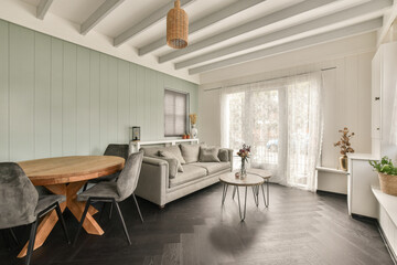 a living room with wood flooring and white painted walls in the room is furnished with grey sofas and chairs
