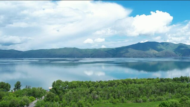 Lake view while driving on road. Trees near Sevan lake In Armenia, Caucasus.  Moving camera show lake, trees, clouds and mountains.  
