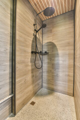 a shower room with wood walls and tile flooring on the wall, there is an open shower stall that has a hand held
