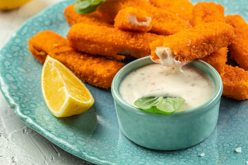Crispy fried fish fingers served with sauce tartar. Food recipe background. Close up
