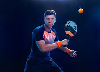 Beach tennis player with racket. Man athlete playing isolated on black background. - 663335108