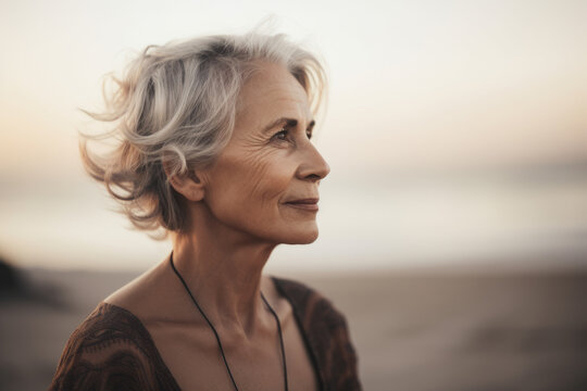 Mature woman with short grey hair happy taking a walk on a beach in autumn