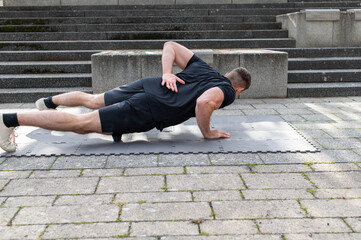 Young man doing a one arm push-up outdoors on concrete background