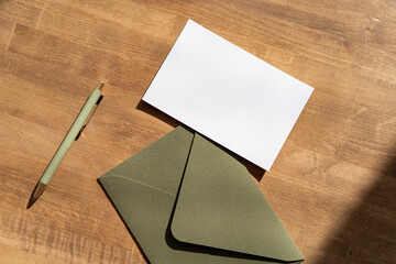 Blank sheet of paper on brown envelope, pen on the desk. Greeting, wedding or congratulations...