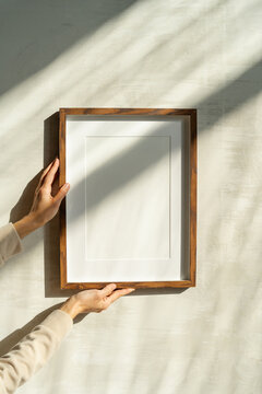 Close-up of female hanging wooden frame with empty mockup copy space. Art concept with shadows and light