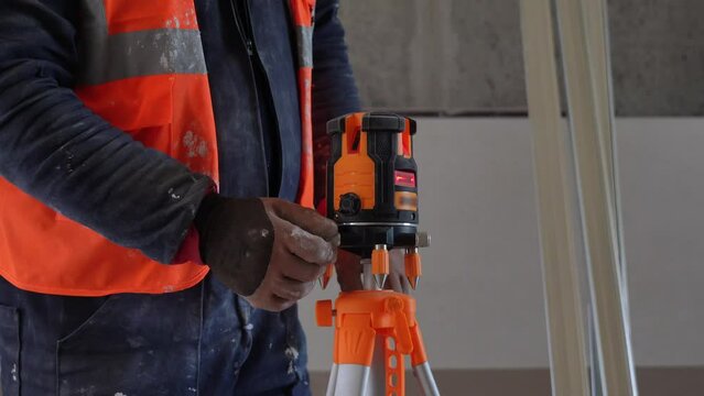 A construction worker utilizing an electronic laser level for precise measurements and leveling at the construction site.