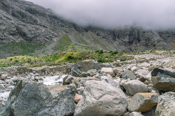 At the foot of the mountain there are huge granite boulders. Rocks that fell from the top of the mountain as a result of an avalanche. Solid rock. Thick white fog at the top of the mountain.