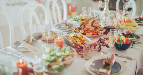 Establishing Shot Without People with Beautiful Christmas Table with a Roasted Turkey Dish, Vegetable Garnishes, Baked Potatoes, Variety of Salads, Decorative Elements and Candlelights