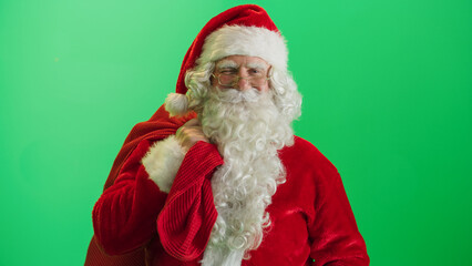 Studio Shot Isolated Mockup Template: Jolly Santa Claus Standing On Green Screen Chromakey Background With Hands Crossed, Looks At the Camera And Winks. Christmas, New Year, Holiday Celebration