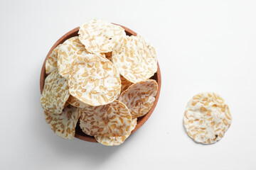 Keripik Tempe or Tempeh Chips are made from soybeans and served on a wooden plate. Isolated on white background.