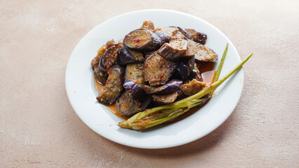 (Terong Balado) Balado eggplant served on a white plate. Single object. Table tops.