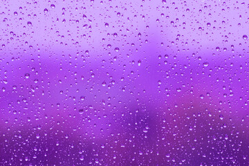 Water drops on glass surface over blurry colored background