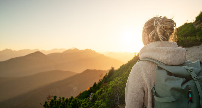 Junge Frau wandert durch die Berge und genie&szlig;t den atemberaubenden Sonnenuntergang
