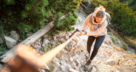 Junge Frau klettert am Klettersteig und sichert sich an einem Stahlseil - obrazy, fototapety, plakaty