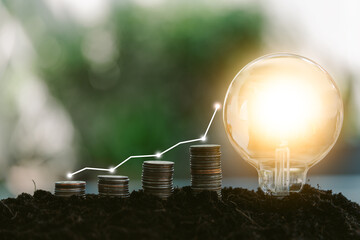 Step stacked coins and light bulbs on the soil with a step up graph, saving finance and energy...
