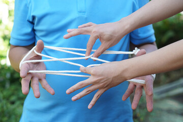 Close up two men playing with rope traditional game called cat cradle, use hands to hold  and...