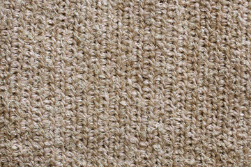 Crocheted fabric made from a combination of jute and viscose threads. Natural handmade fabric for a rug, sofa upholstery or bag. Craft, background, texture.