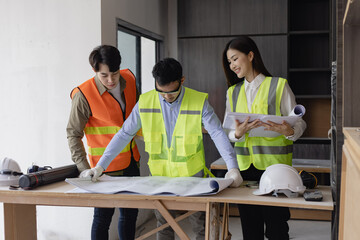 Construction and structure project concept. Engineering team meeting planning with paper plans at construction site.