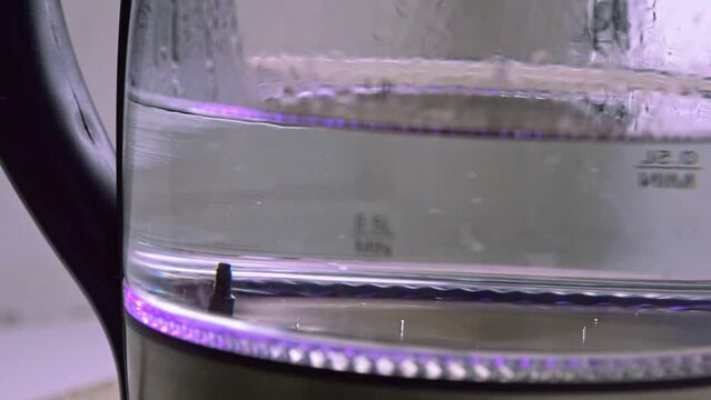 water boils to 90 degrees Celsius in a glass kettle, close-up