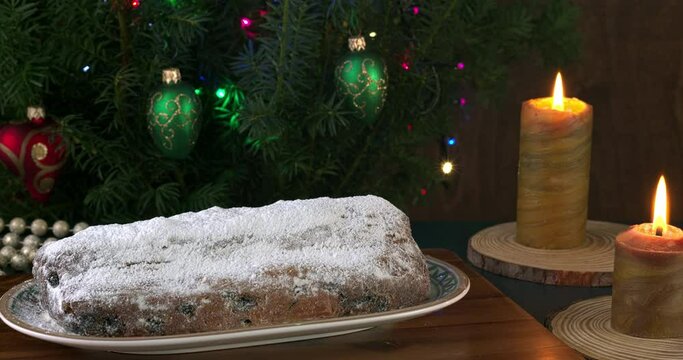 Spreading sugar powder on stollen traditional cake on a Christmas decorated table.
